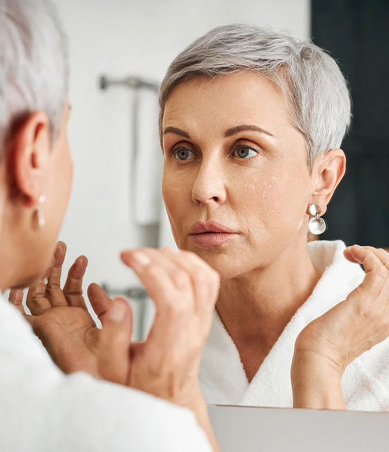 Older woman looking in the mirror at her smooth skin