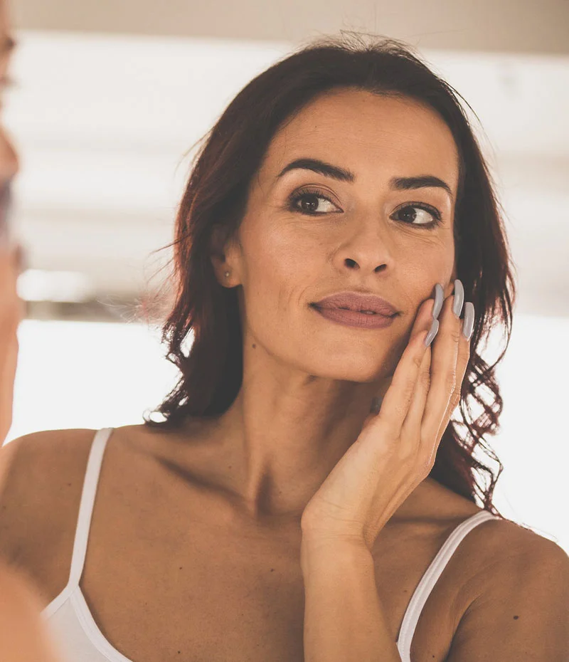 Middle age woman looking at her skin in a mirror